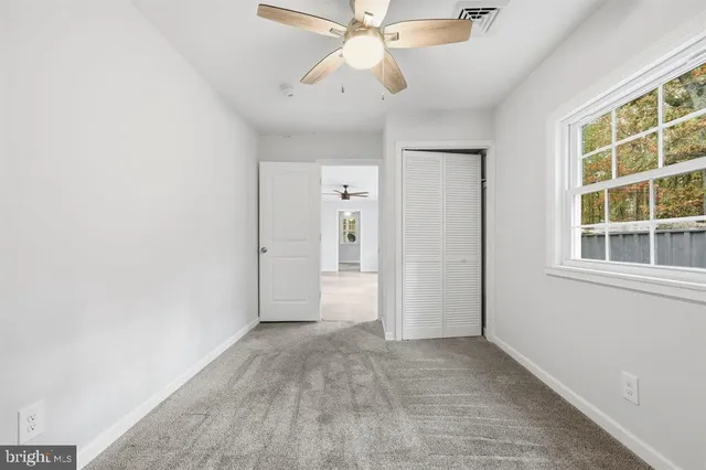 an empty room with chandelier fan and windows