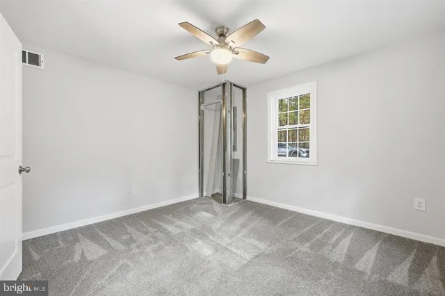 an empty room with windows and ceiling fan