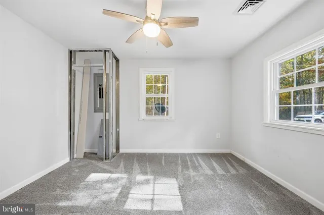 an empty room with windows and fan