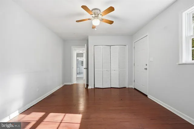 a view of an empty room with window and a fan