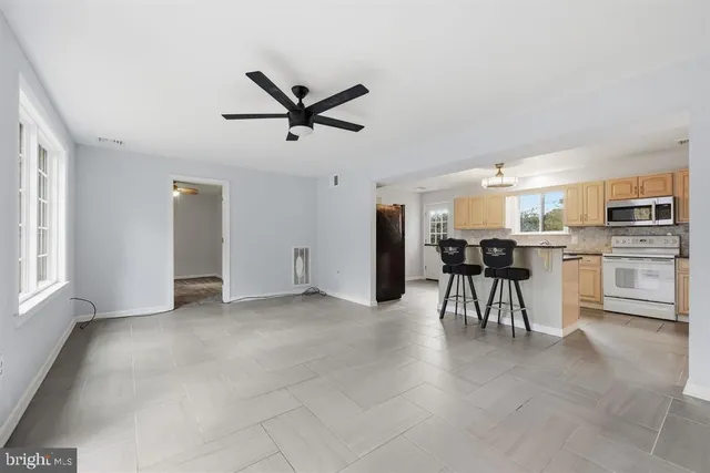 a view of a livingroom with furniture a ceiling fan and kitchen view