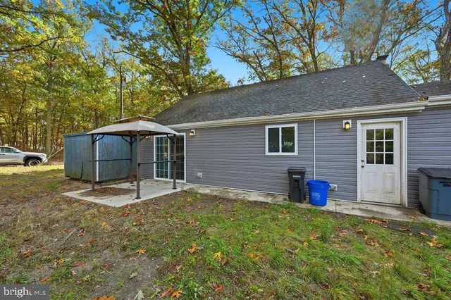 a backyard of a house with table and chairs under an umbrella
