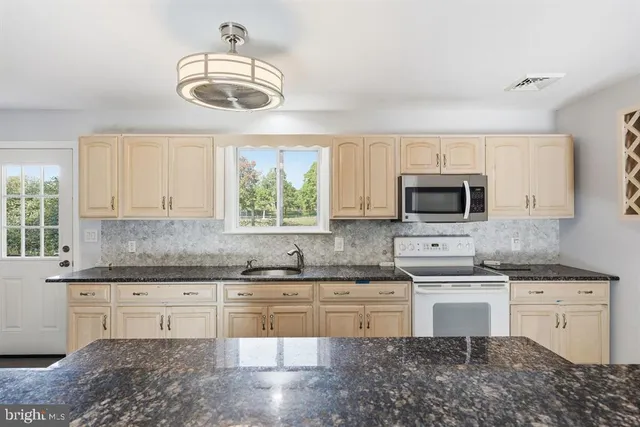 a kitchen with stainless steel appliances granite countertop a stove a sink and a microwave