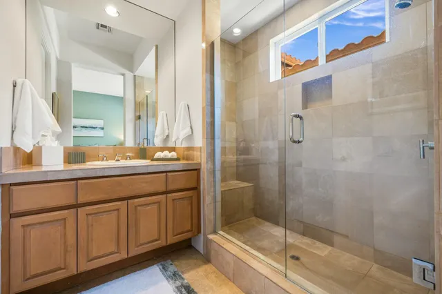 a bathroom with a granite countertop sink a toilet a mirror and shower
