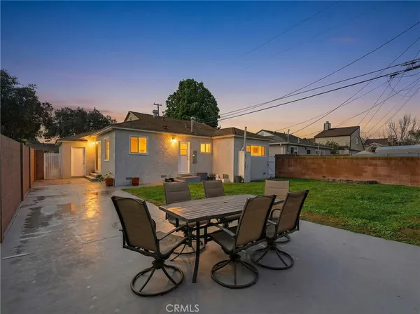 a view of a patio with table and chairs with plants and wooden fence
