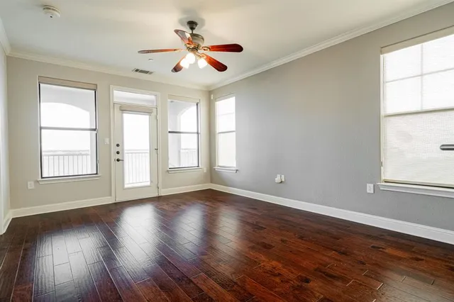 a view of an empty room with a window and wooden floor