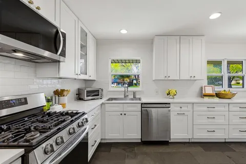 a kitchen with stainless steel appliances white cabinets and a stove top oven