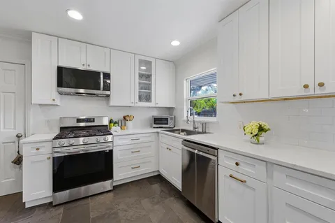 a kitchen with stainless steel appliances white cabinets and a stove top oven