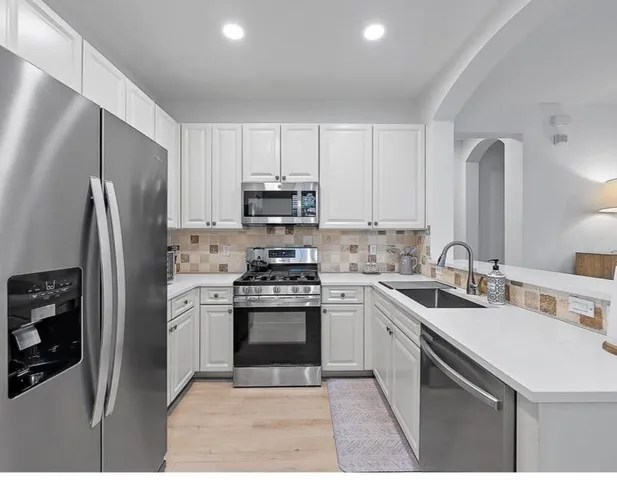 a kitchen with stainless steel appliances granite countertop a sink stove refrigerator and cabinets