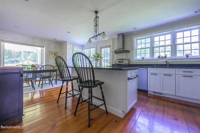 a kitchen with stainless steel appliances granite countertop dining table chairs a refrigerator and cabinets