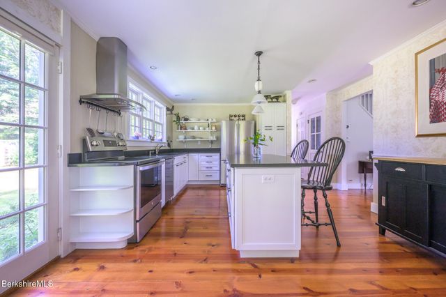 a kitchen with stainless steel appliances granite countertop a stove top oven a sink a dining table and chairs
