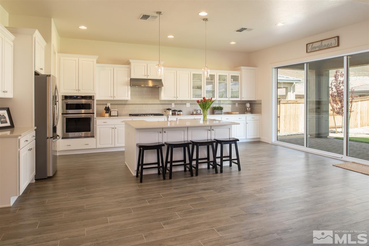 9840 Gainsborough Lane Reno, NV 89521 - Photo 6 of 24 a kitchen with kitchen island granite countertop a stove a refrigerator and a dining table