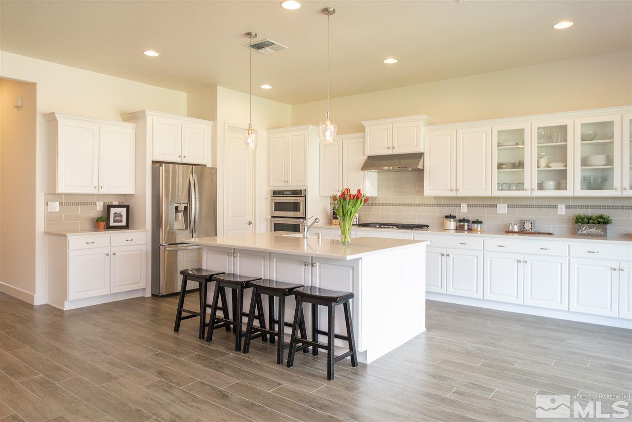 9840 Gainsborough Lane Reno, NV 89521 - Photo 7 of 24 a kitchen with stainless steel appliances granite countertop a refrigerator a stove and white cabinets with wooden floors