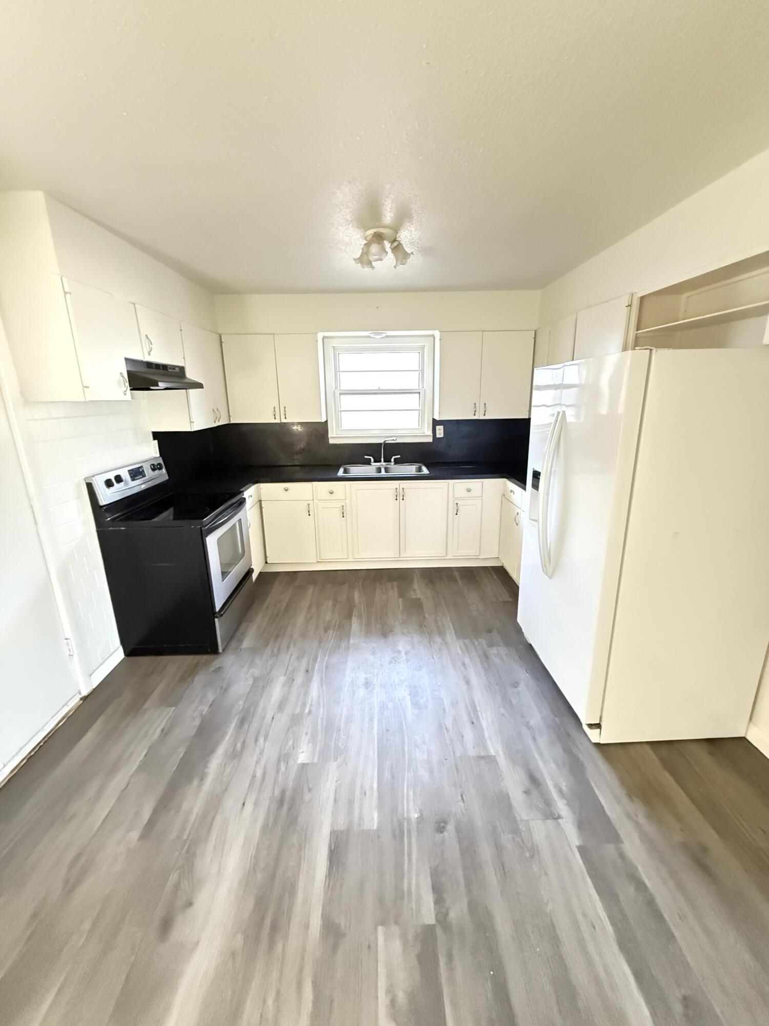 a kitchen with wooden floors and refrigerator