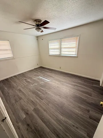 an empty room with wooden floor cabinet and windows