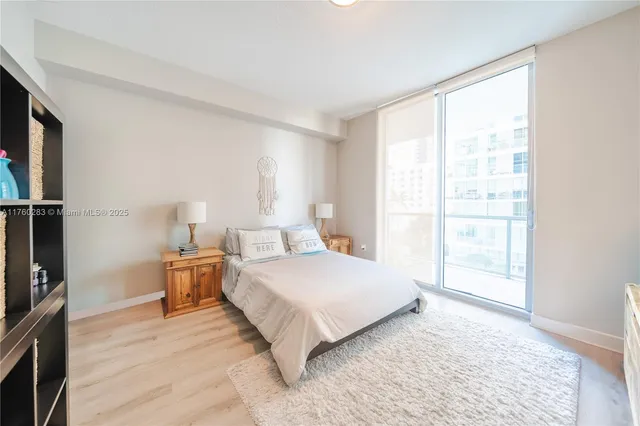 a bedroom with a bed wooden floor and a large window