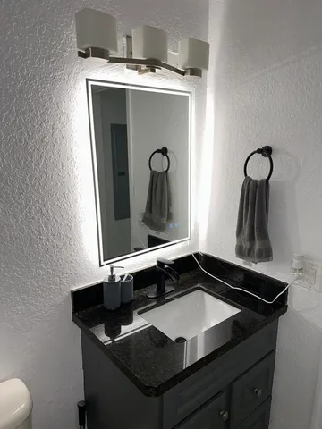 a bathroom with a granite countertop sink and a mirror