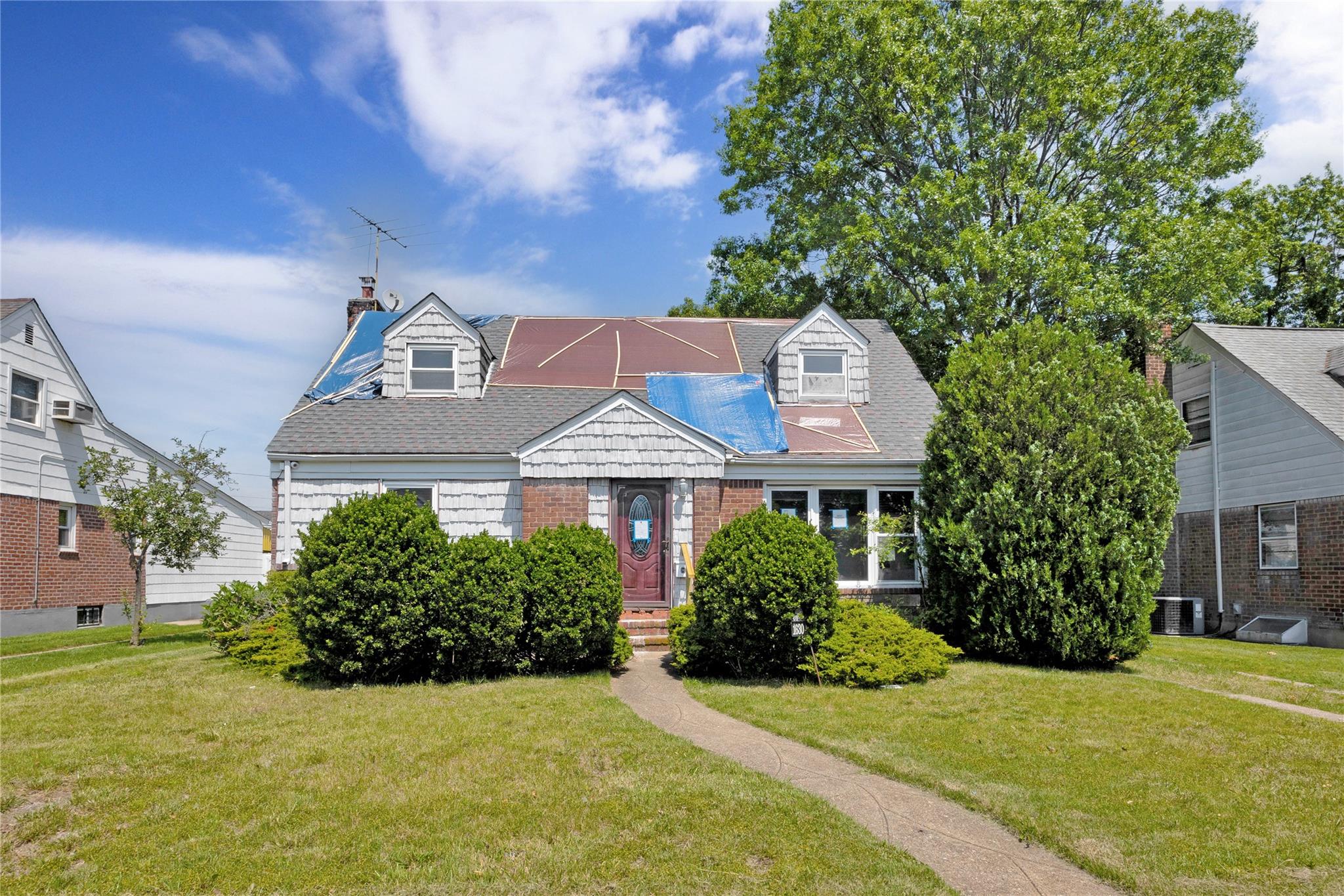 1630 Salem Road Valley Stream, NY 11580 - Photo 1 of 1 Cape cod-style house featuring a front yard, a chimney, cooling unit, brick siding, and roof with shingles