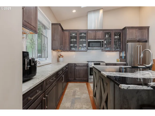 a kitchen with stainless steel appliances granite countertop a sink counter space cabinets and a large window