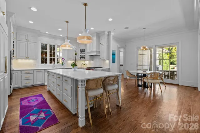 a kitchen with stainless steel appliances granite countertop a kitchen island hardwood floor sink stove dining table and chairs