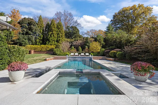 a view of swimming pool with seating space and trees in the background