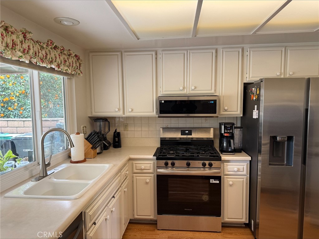 1114 Bottle Tree Way Hemet, CA 92545 - Photo 7 of 23 a kitchen with stainless steel appliances a stove a sink a refrigerator cabinets and a window