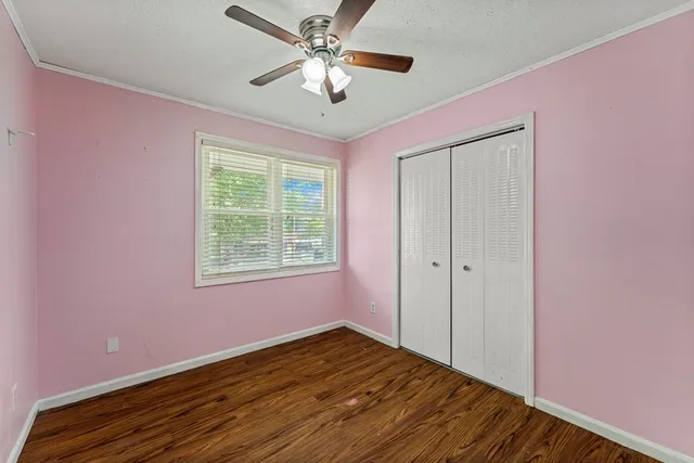 a view of empty room with wooden floor and fan