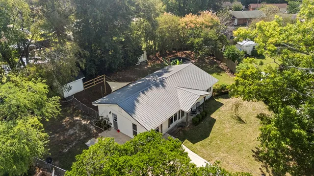 an aerial view of a house with a yard and covered with trees