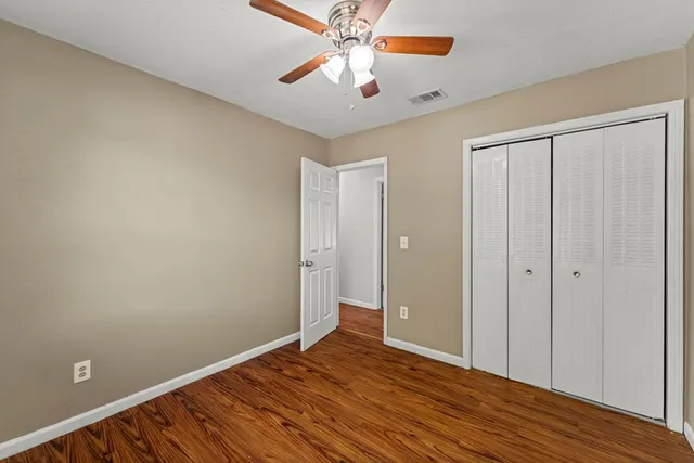a view of an empty room with window and wooden floor