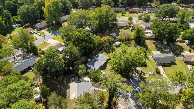 an aerial view of residential houses with outdoor space and trees all around