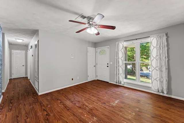 a view of an empty room with wooden floor and a window