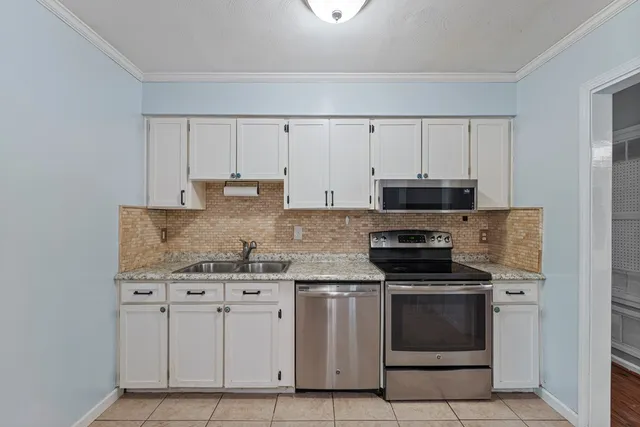 a kitchen with stainless steel appliances granite countertop a stove a sink and a microwave