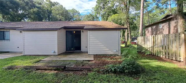 a view of a house with a small yard plants and large tree
