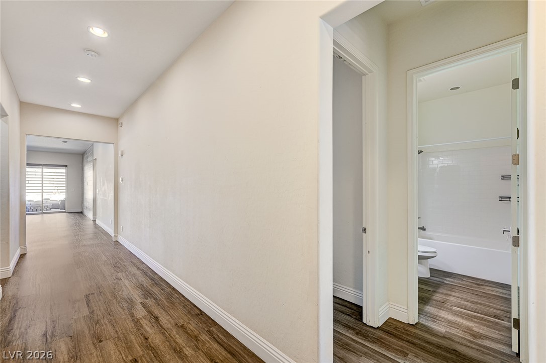 8197 Riley Love Street Las Vegas, NV 89139 - Photo 4 of 48 A lengthy corridor with wood-style flooring extends toward an open living space.