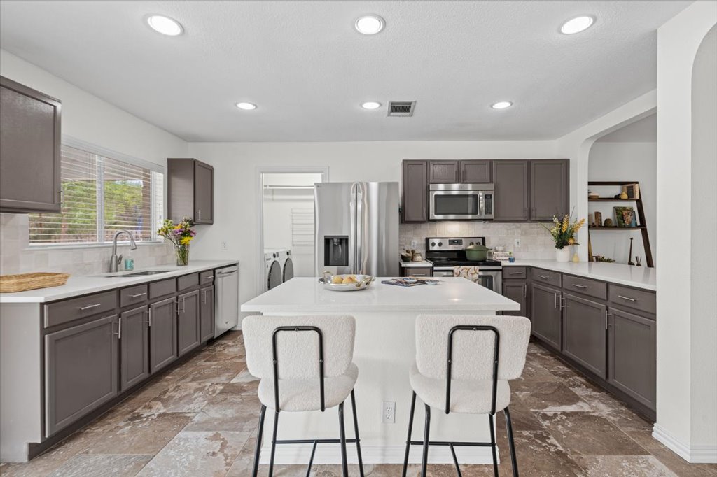 7451 Pusch Ridge Loop Austin, TX 78749 - Photo 10 of 26 Sleek modern cabinetry and stone counters surround a spacious central prep island.