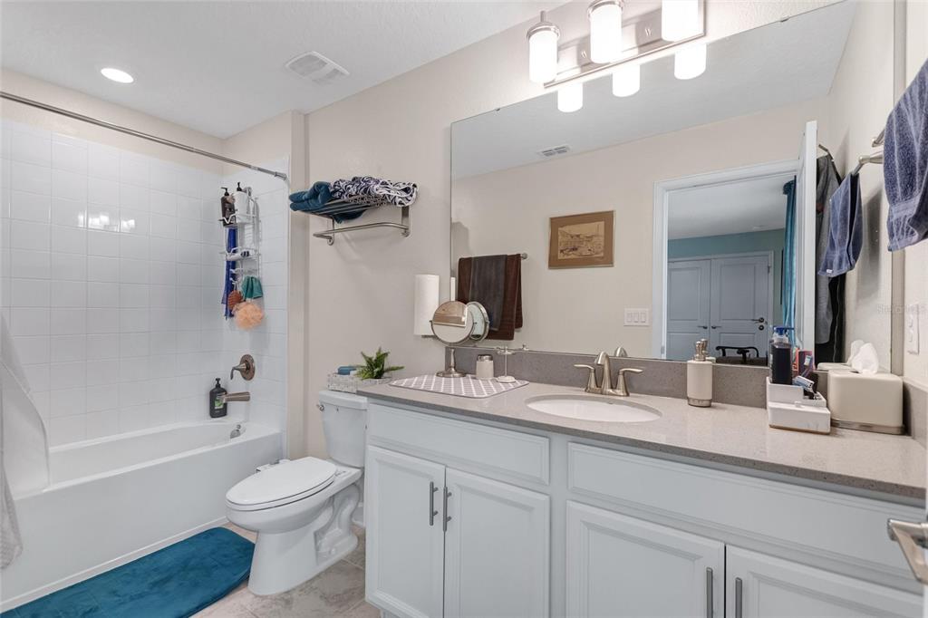 1089 Blackwolf Run Road Davenport, FL 33896 - Photo 32 of 82 a bathroom with a granite countertop sink a toilet a shower and a mirror