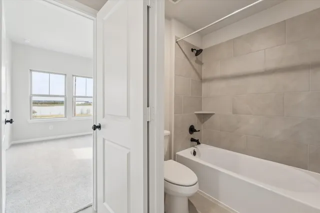 a bathroom with a granite countertop bathtub shower and toilet