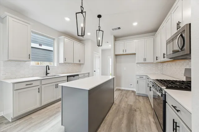 a kitchen with cabinets stainless steel appliances a sink and a window