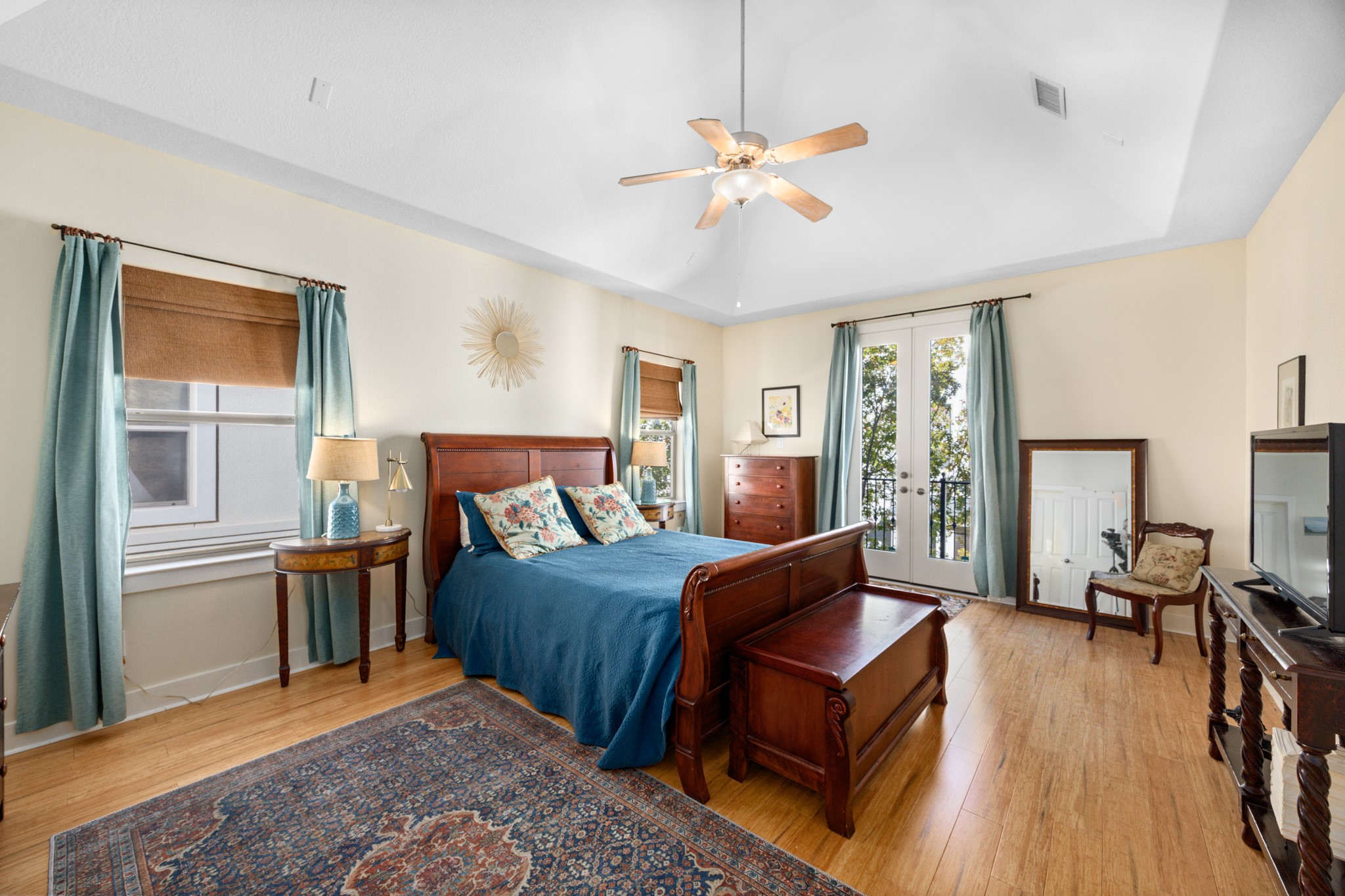 2611 Commonwealth Street Houston, TX 77006 - Photo 21 of 31 The spacious primary bedroom, offers a serene retreat with vaulted ceilings, bamboo floors, and abundant natural light. French doors open to a private balcony. The generous layout easily accommodates a full bedroom suite and sitting area. The primary bedroom is complemented by a stylish en-suite bathroom and a large walk-in closet, providing comfort, functionality, and everyday luxury.