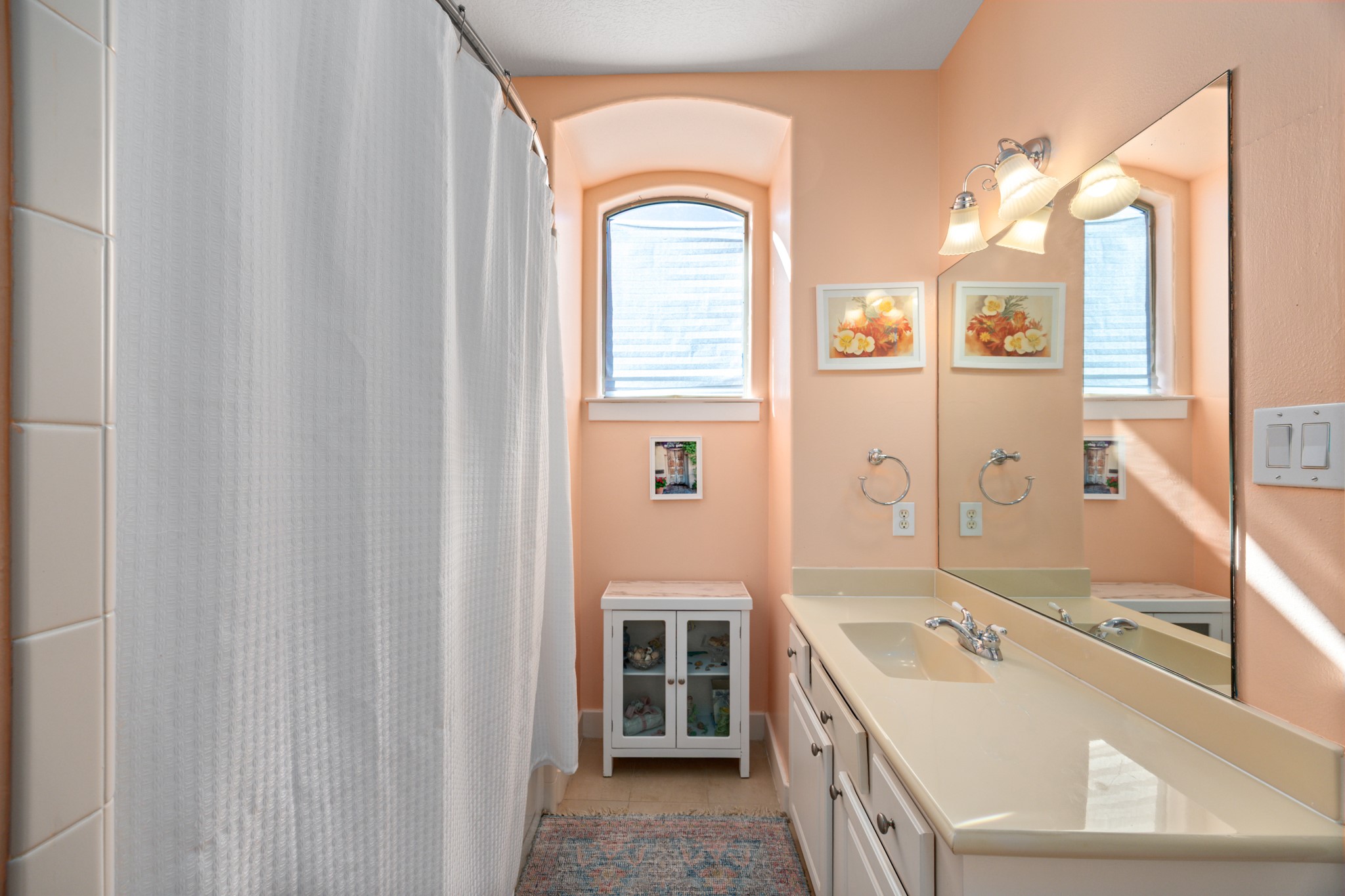 2611 Commonwealth Street Houston, TX 77006 - Photo 28 of 31 This bathroom features a clean, cheerful design with soft, warm tones and abundant natural light. A long vanity with generous counter space and a large mirror enhances functionality, while classic lighting fixtures add a timeless touch.