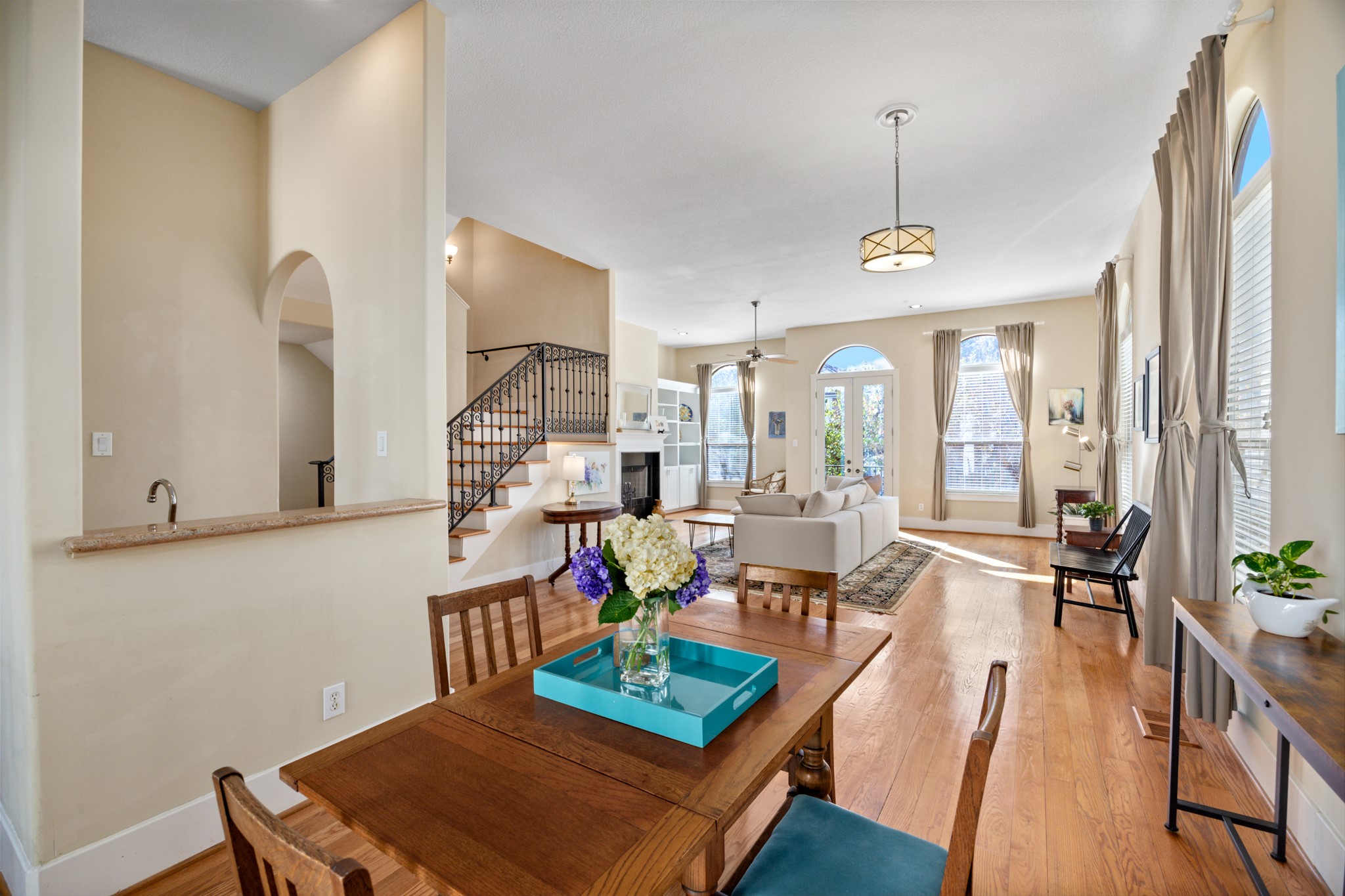 2611 Commonwealth Street Houston, TX 77006 - Photo 9 of 31 The expansive second-floor living level, featuring a generous open-concept layout that seamlessly connects the living room, dining area, bar, and kitchen, ideal for both entertaining and everyday living. Warm hardwood floors and soaring ceilings create a grand sense of scale, while oversized windows and French doors flood the space with natural light. Two balconies extend the living area outdoors, offering inviting spots for morning coffee or evening gatherings.