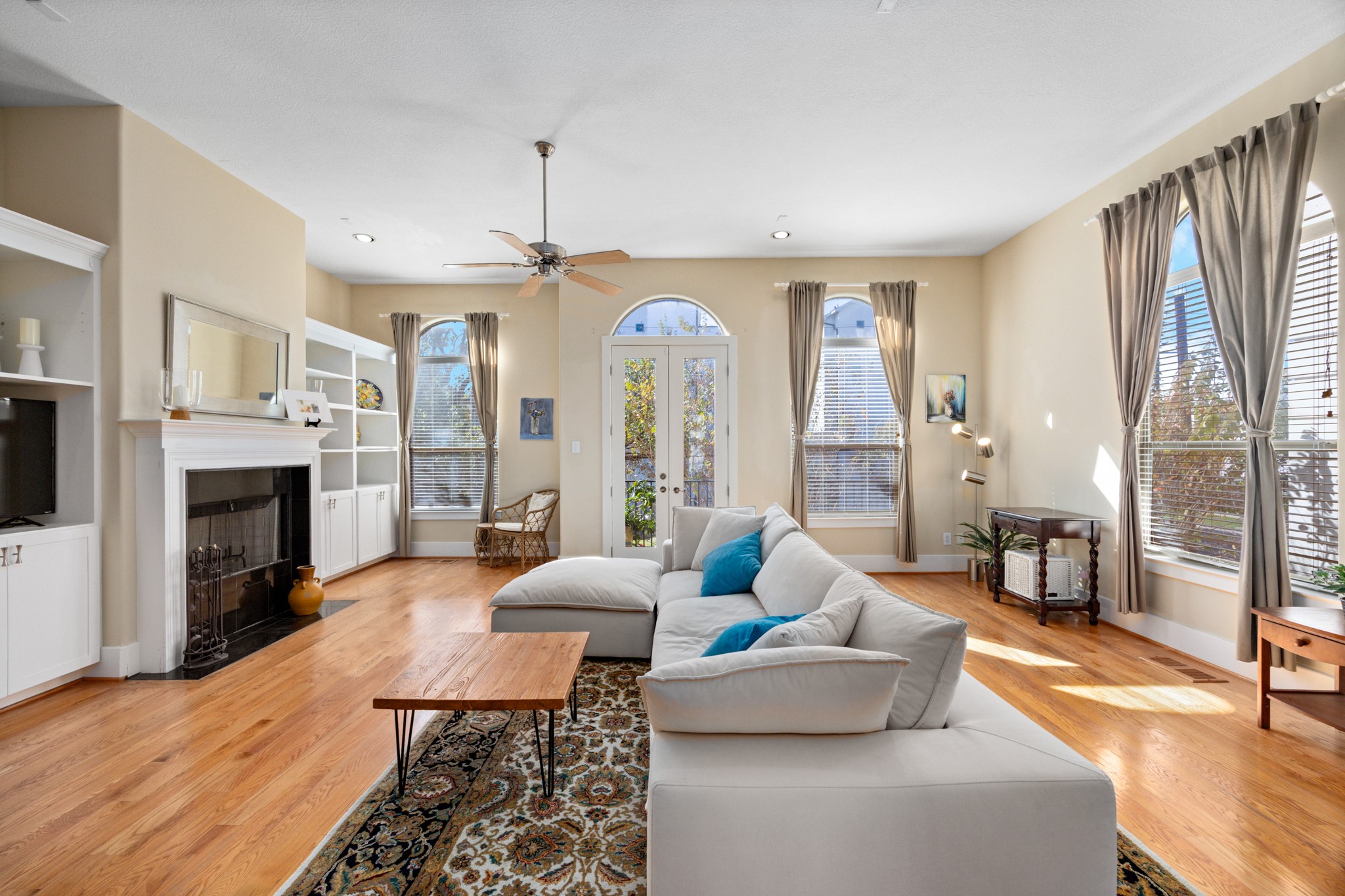 2611 Commonwealth Street Houston, TX 77006 - Photo 10 of 31 Bright and sophisticated living room designed for both comfort and entertaining. Warm hardwood floors anchor the space, while built-in shelving and a classic fireplace add timeless elegance and architectural interest. Expansive windows and French doors flood the room with natural light and open to a private balcony.