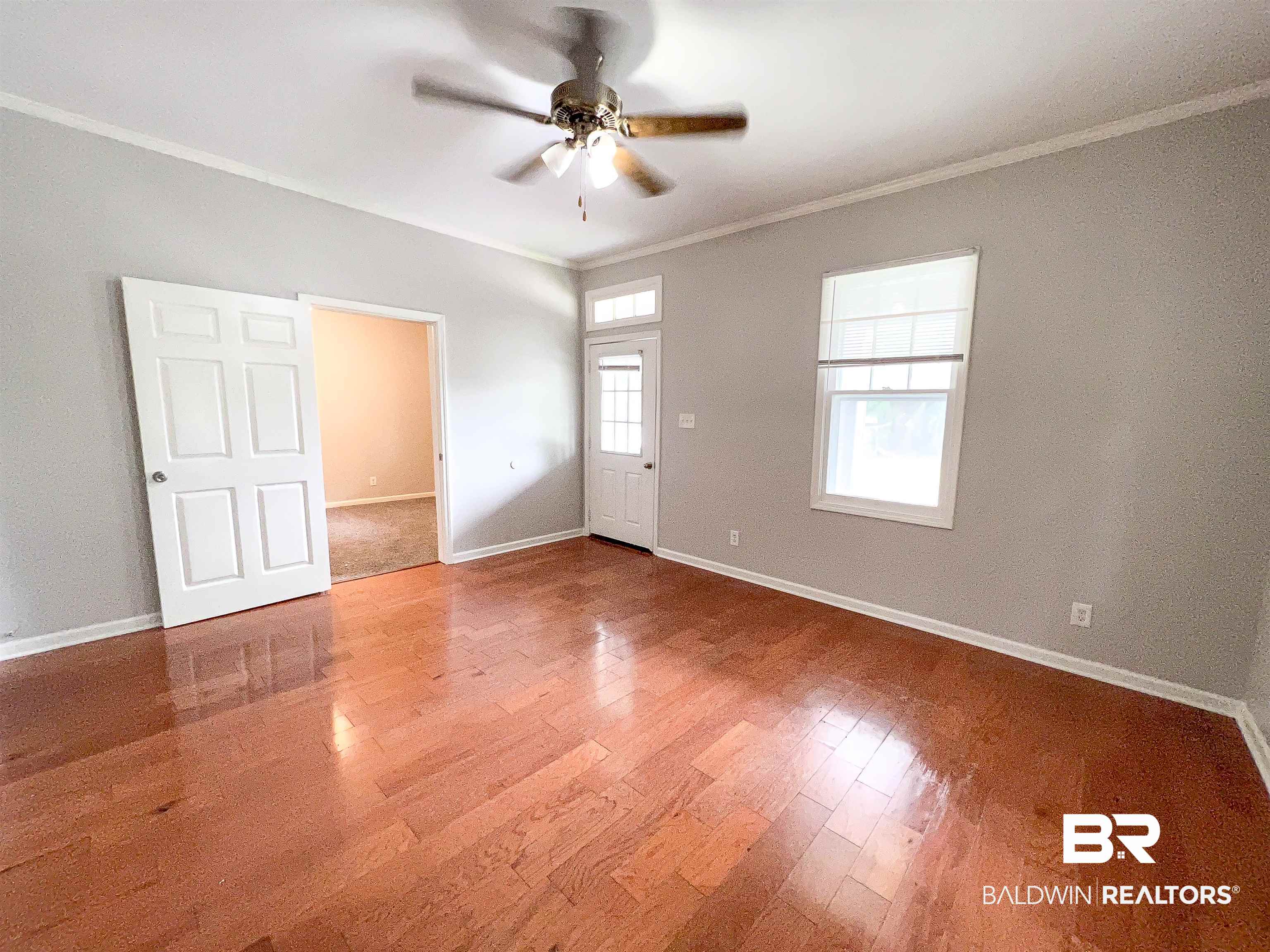 1164 Seneca Street Mobile, AL 36605 - Photo 5 of 22 Empty room featuring a ceiling fan, crown molding, baseboards, and wood finished floors