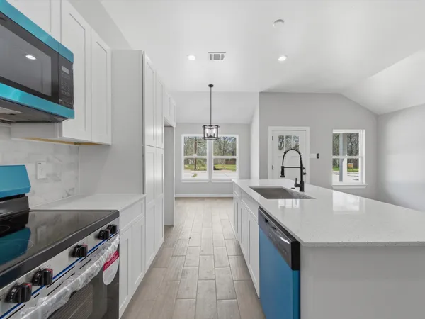 a kitchen with stainless steel appliances a stove top oven a sink a refrigerator and white cabinets