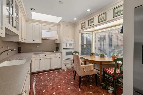 a open kitchen with stainless steel appliances granite countertop a stove a sink dishwasher and a refrigerator with white cabinets