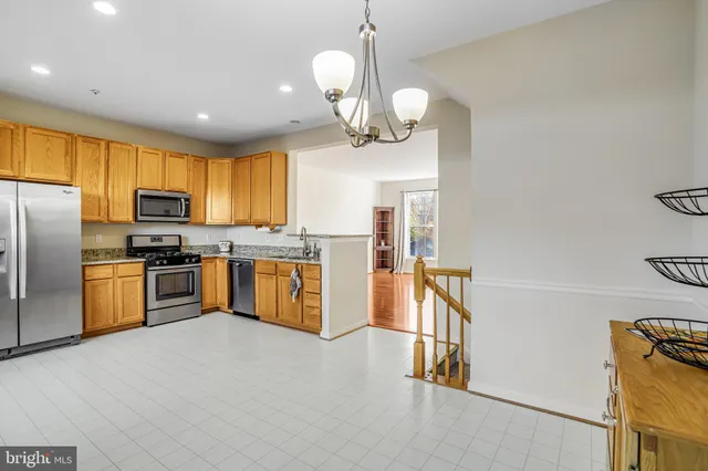 a kitchen with stainless steel appliances granite countertop a sink a stove a refrigerator cabinets and chairs