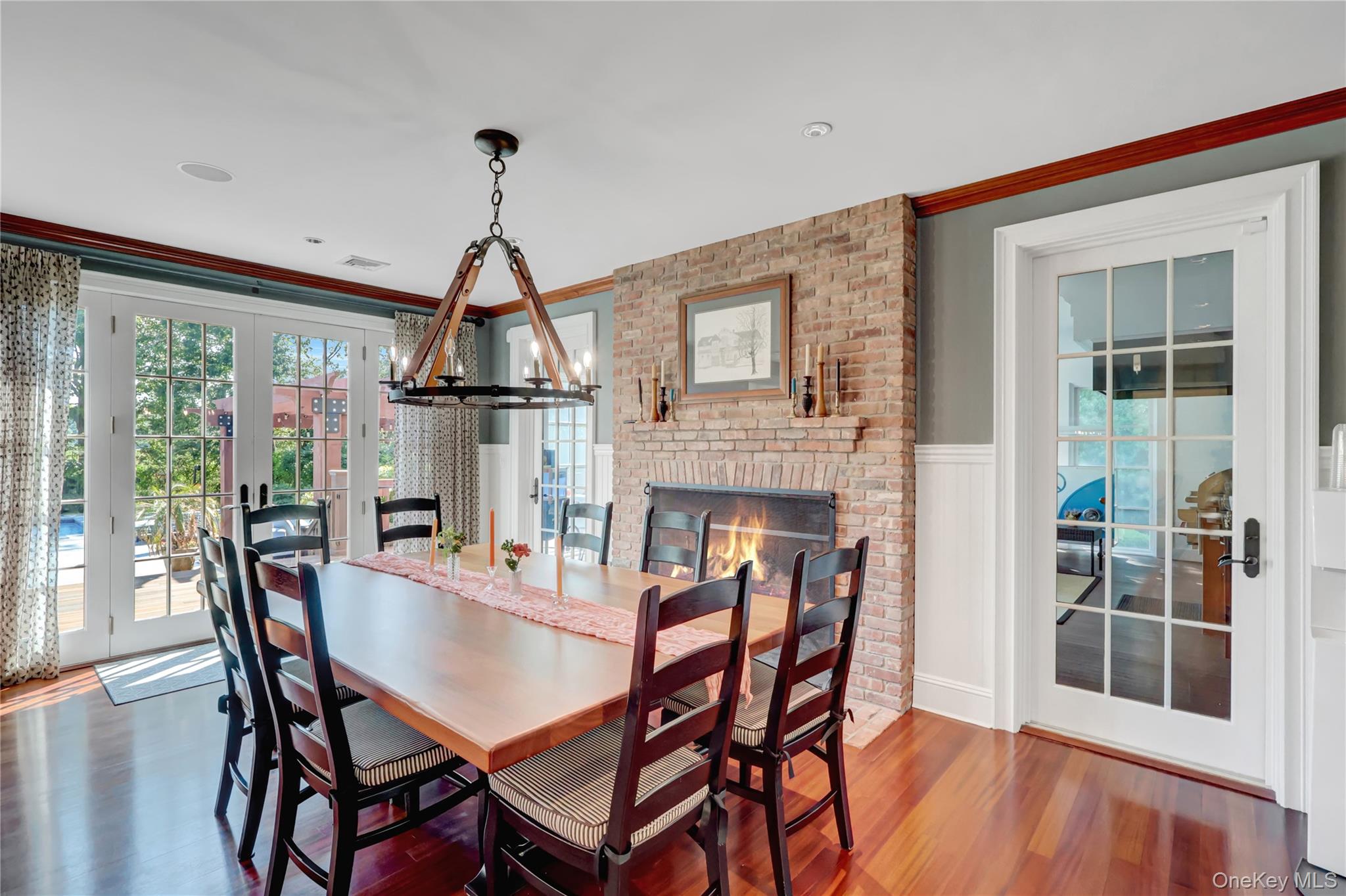 63 Dyke Road Setauket, NY 11733 - Photo 12 of 49 Dining room with french doors, plenty of natural light, a chandelier, a fireplace, and wainscoting
