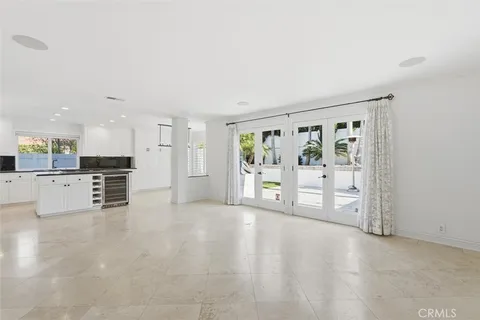 a view of an empty room with kitchen and window