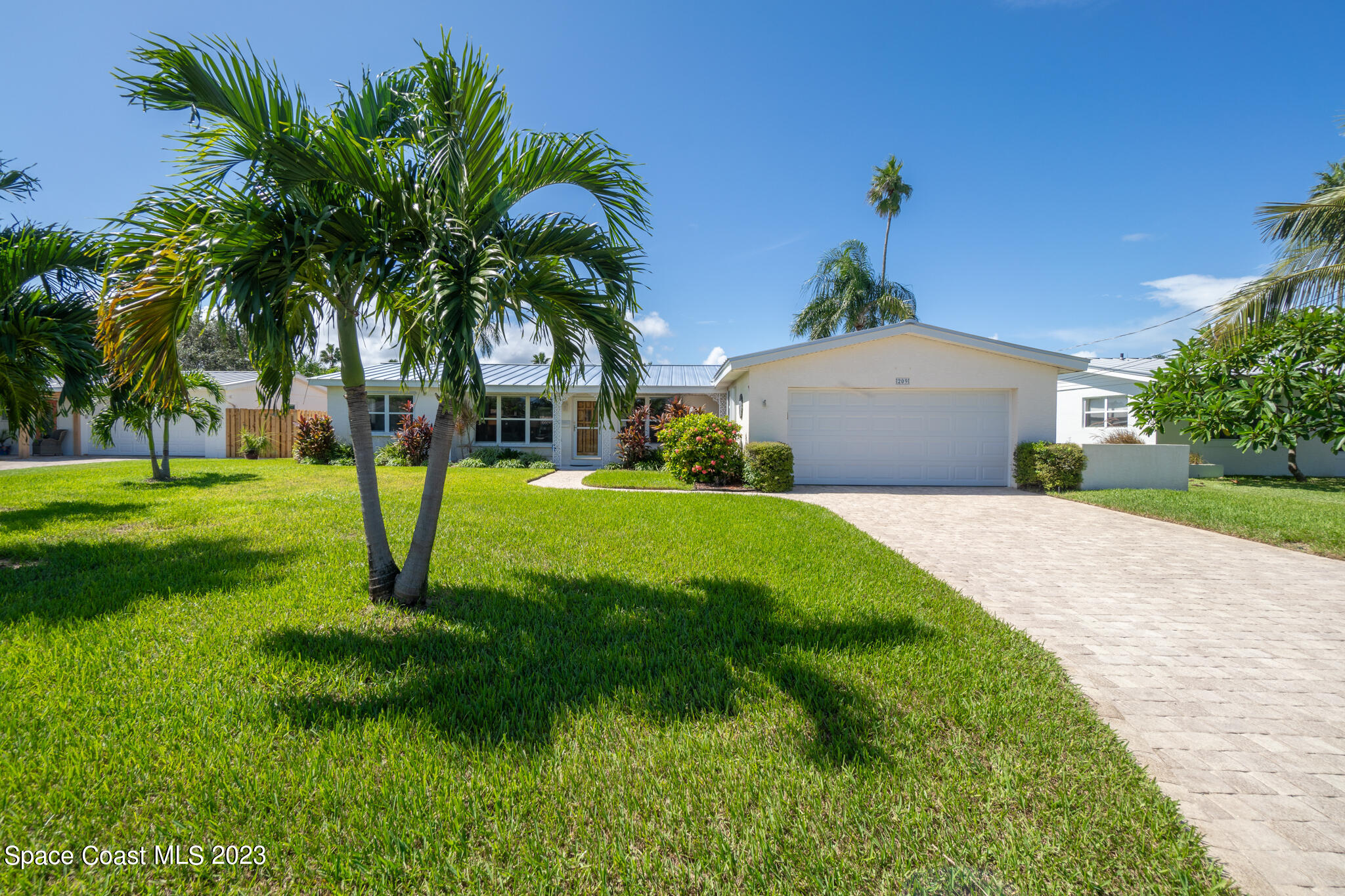 209 River Road Satellite Beach, FL 32937 - Photo 28 of 86 a front view of a house with a yard and palm trees
