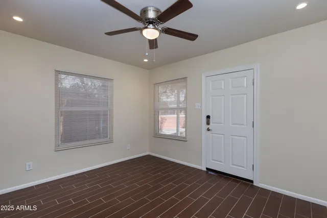 a view of an empty room with wooden floor and a window